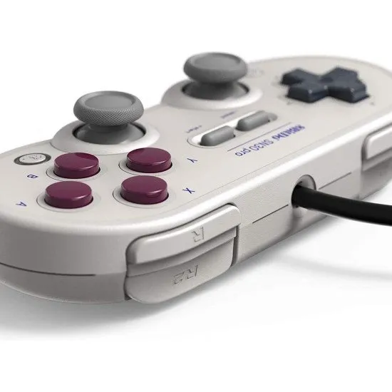 A retro-styled grey controller with purple face buttons and dual analogue sticks, inspired by classic 8-bit handheld aesthetics