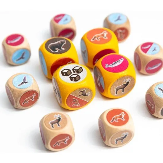 Colourful dice featuring animal icons alongside illustrated habitat sheets and cards depicting the rolling hills of Cascadia