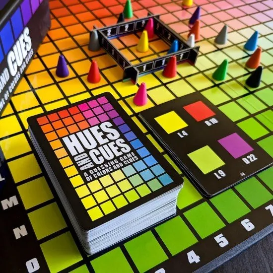 The box art for the Hues and Cues board game, featuring a colorful grid of hues with game pieces on it.